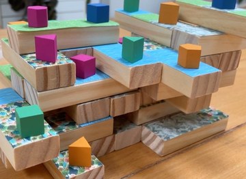 stacked wooden blocks with colorful terrain tiles and game pieces